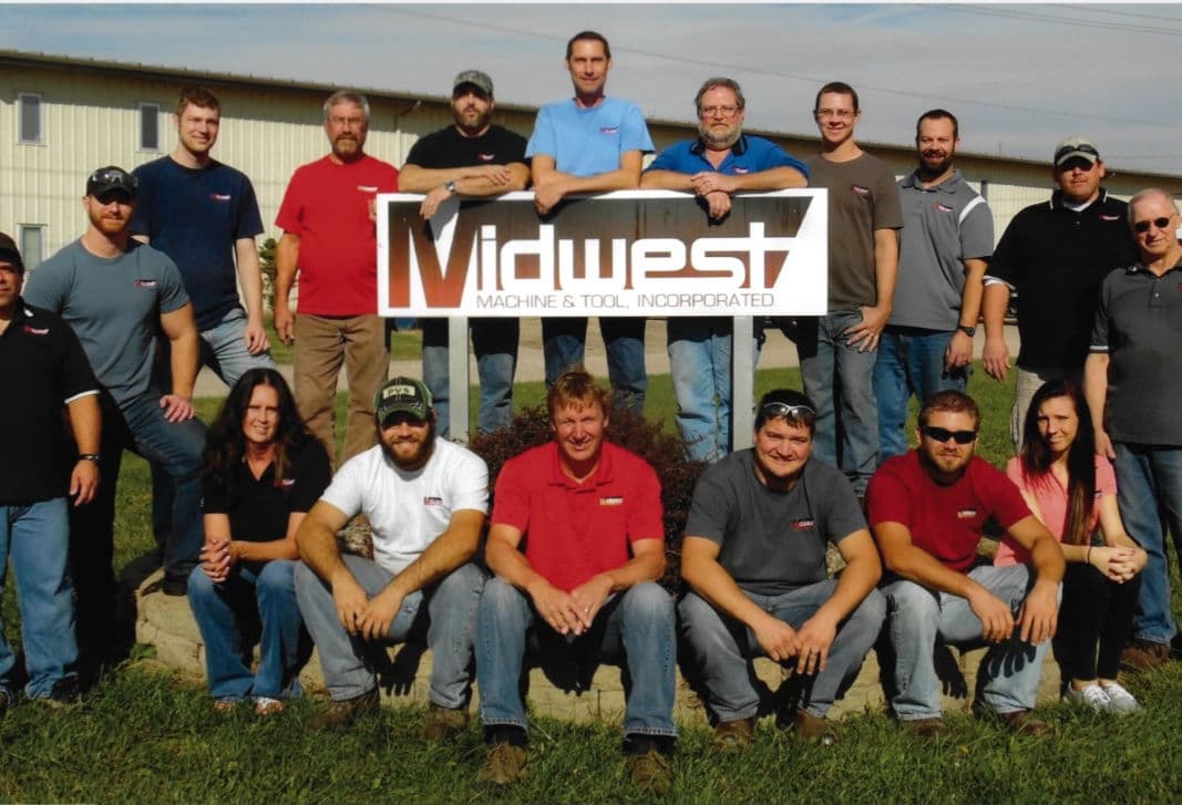 Midwest Machine & Tool team gathered in front of the company sign